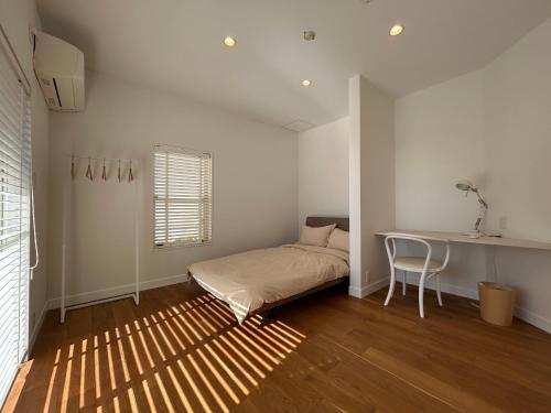 a bedroom with a bed and a desk and a table at Smile House Akiya in Hayama