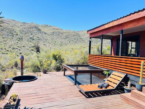 a house with a deck with a bench and a table at Matilo Cabins - Cactus Deck with Hot-tub and Fireplace in Calitzdorp
