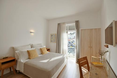 een slaapkamer met een bed en een deur naar een balkon bij NESEA VIEW Boutique Apartments in Hydra