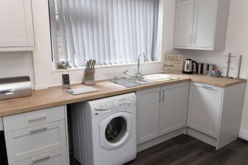 a kitchen with a washing machine and a sink at The Standhouse Radcliffe in Radcliffe