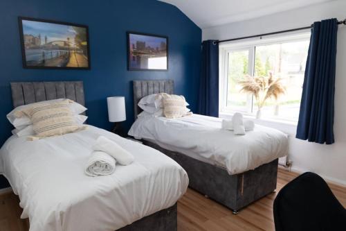 two beds in a room with blue walls and a window at The Standhouse Radcliffe in Radcliffe