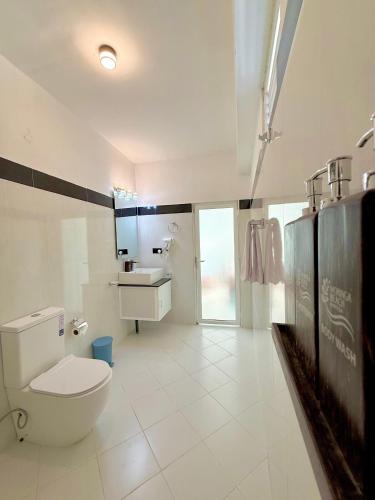 a white bathroom with a toilet and a sink at Moringa Beach in Mirissa