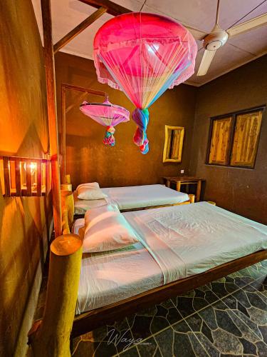two beds in a room with pink umbrellas hanging from the ceiling at Elephant paradise Safari resort in Udawalawe