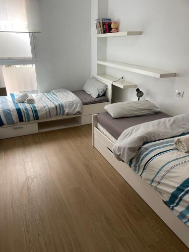 two beds in a room with wooden floors at PLAYA ALMARDA CORINTO, PISCINA, WIFI,2 TERRAZAS, BARBACOA,TRANQUILo in Sagunto
