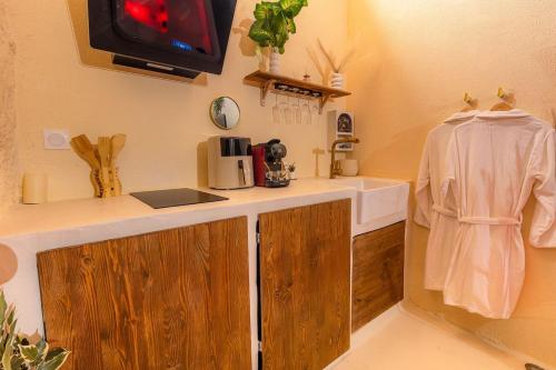 a kitchen with a counter and a tv on the wall at Écrin Secret - Suite troglodyte avec spa in Pia