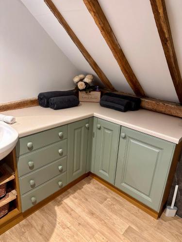 a bathroom with a green dresser in a attic at The Granary in Hurstpierpoint