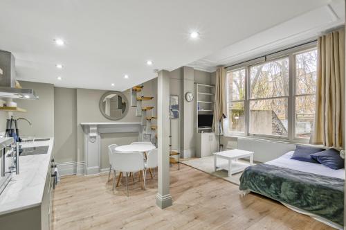 a bedroom with a bed and a kitchen and a table at Well Appointed Garden Condo in Kensington Olympia in London