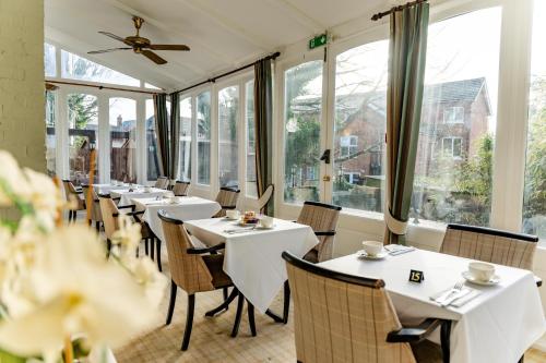 a restaurant with white tables and chairs and windows at The Falcon Hotel in Farnborough