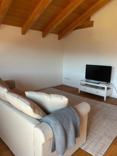 a living room with a white couch and a tv at Servus Chiemgau - Große Wohnung mit Bergblick in Frasdorf