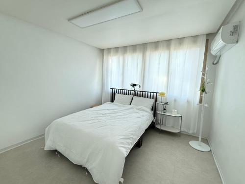 a white bedroom with a bed and a window at 휘게스테이 in Sejong