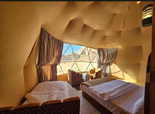 a room with two beds and a large window at Wadi rum Rozana camp in Wadi Rum