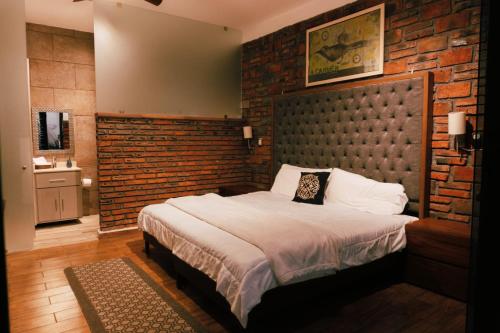 a bedroom with a large bed and a brick wall at Hotel Boutique in Querétaro