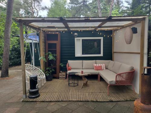 a couch sitting under a pergola on a patio at Chalet De Maanvaren in Hattemerbroek