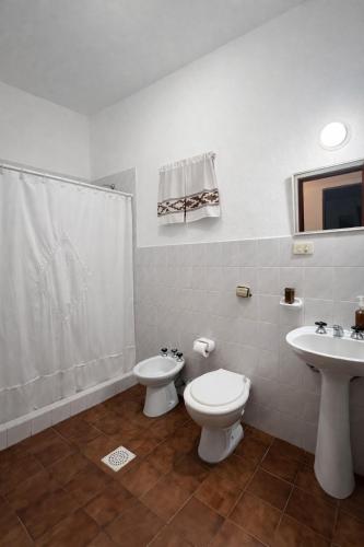 a white bathroom with a toilet and a sink at El Bosque de Simba - Casa in La Estancia