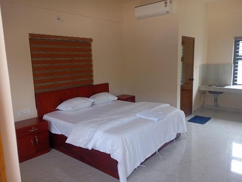 a bedroom with a white bed with two pillows at PURAYIL Rooms in Kozhikode