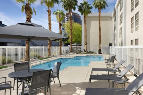 a patio with tables and chairs and a pool with palm trees at Fairfield Inn Las Vegas Convention Center in Las Vegas