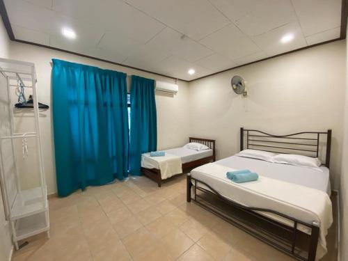 a bedroom with two beds and a blue curtain at La villa June by Juniar Place in Kampong Ulu Pegoh