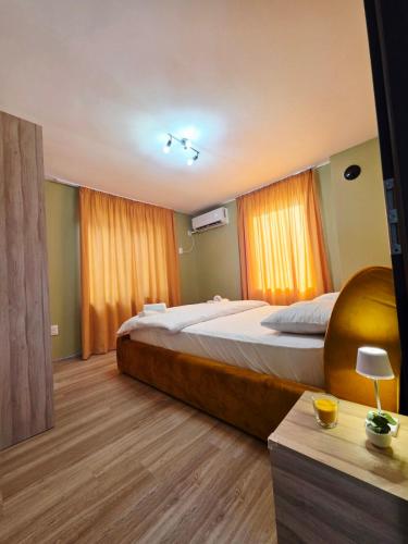 a bedroom with a large bed with orange curtains at Charshiq Guest House in Veliko Tŭrnovo