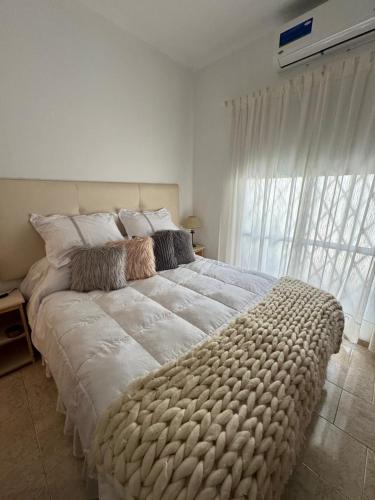 a large bed in a bedroom with a large window at VIA VALENTINA "el deseo de volver" departamentos temporales sobre Av Eden centro in La Falda