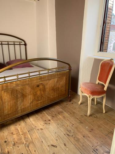 a bedroom with a wooden bed and a chair at Maisonnette ardéchoise au centre du village in Nozières