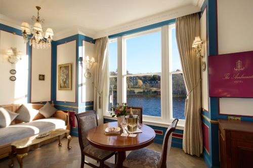 a living room with a table and a large window at The Ambassador Hotel in Inverness