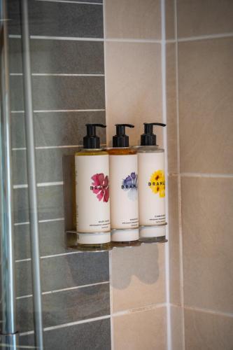three bottles ofodorizers sitting on a shelf in a bathroom at Tewinbury Farm Hotel in Tewin