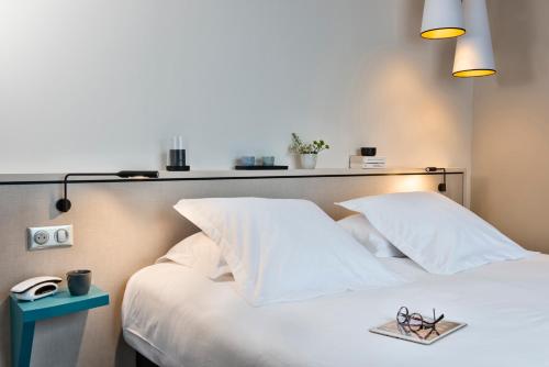 a bedroom with a white bed with white pillows at Hôtel la Baie Valdys Resort & SPA in Douarnenez