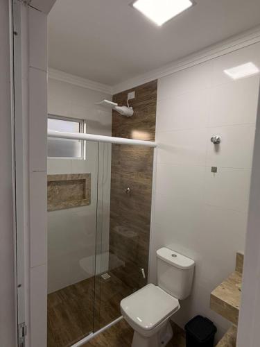 a bathroom with a toilet and a glass shower at Flats Privativos MaragoJulios in Maragogi