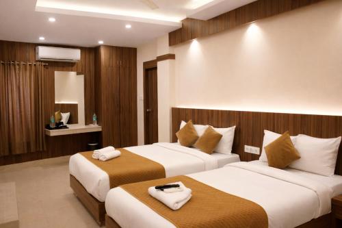 a hotel room with two beds with towels on them at Hotel Sakura Inn in Hosūr