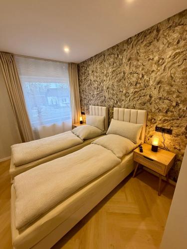a large bed in a room with a stone wall at Ferienwohnung Luna in Eppelborn