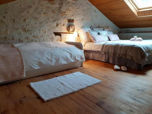a bedroom with two beds and a lamp and a rug at Prouyssou in Beauville
