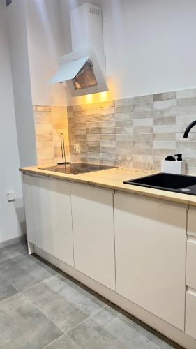 a kitchen with white cabinets and a sink at Apartament Tarasy Wenecji 2 in Gniezno