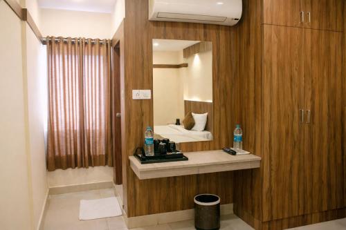 a bathroom with a mirror and a bed in a room at Hotel Sakura Inn in Hosūr