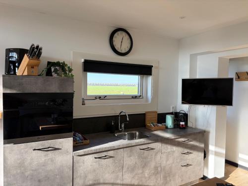 a kitchen with a sink and a clock on the wall at B&B de Danser in Klaaswaal