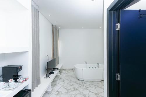 a bathroom with a bath tub and a sink at Villa Santorini Boutique & Hotel in Pirenópolis