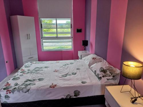 a bedroom with pink and purple walls and a bed at Los Adobes in Cerrillos