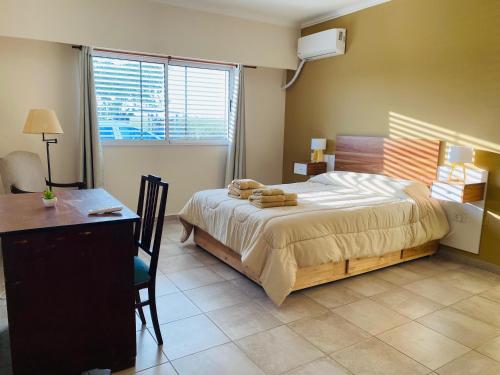 a bedroom with a bed and a desk and a window at Las Agujas in Aldea Camarero