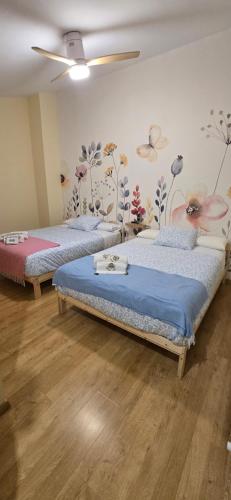 two beds in a room with flowers on the wall at Mirador del Torreón in Alcañiz
