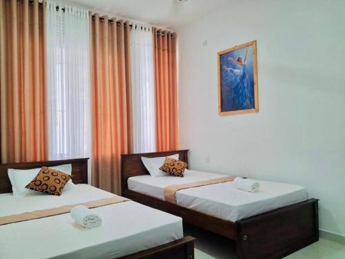 a room with two beds and a picture on the wall at Kandy Rainbow Villa in Kandy
