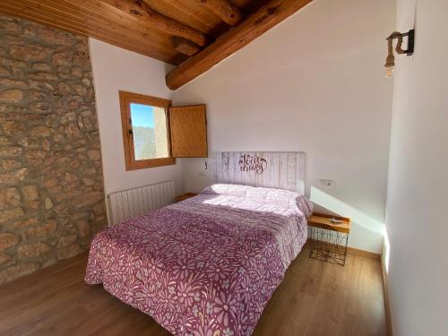 a bedroom with a bed and a stone wall at Cal Perico in San Pedro Sallavinera