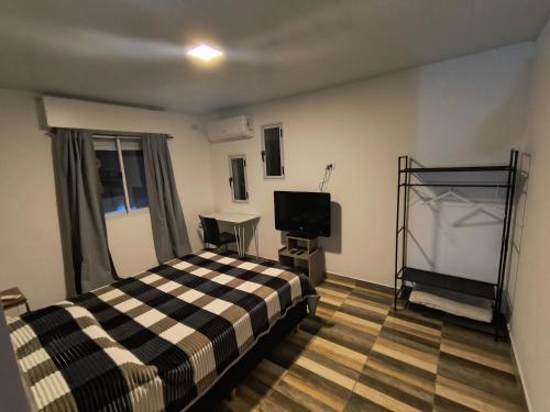 a bedroom with a bed and a flat screen tv at Bajo el Sauce in Ranchos