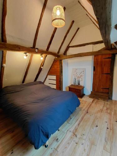 a bedroom with a blue bed in a attic at La Fontaine du Peuch in Plazac