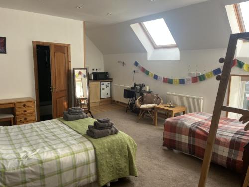 a bedroom with two beds and a table and a kitchen at Broomhead Cottages in Dufftown