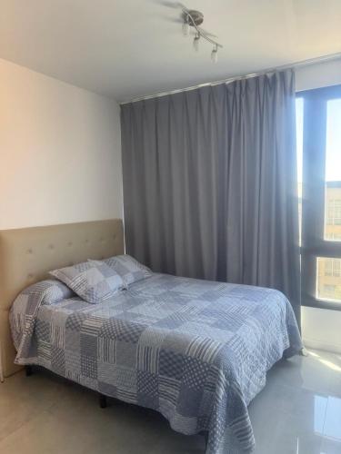 a bedroom with a bed with a blue blanket and a window at Brickell 6SIX in Tigre