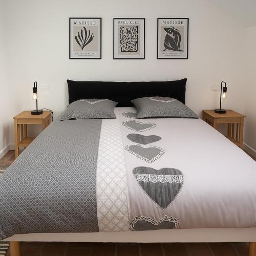 a bed with a gray bedspread with hearts on it at Gîte des Templiers in Couches