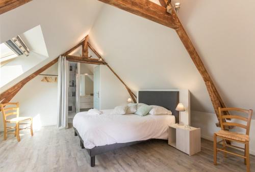a bedroom with a white bed in a attic at Le Relais des Flâneurs in Thaon