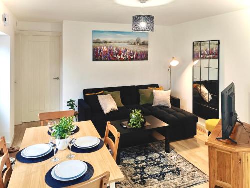 a living room with a black couch and a table at Charming Apartment Nottingham -FREE Onsite Parking -Nr City- FAST WiFi in Nottingham