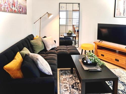 a living room with a black couch and a tv at Charming Apartment Nottingham -FREE Onsite Parking -Nr City- FAST WiFi in Nottingham