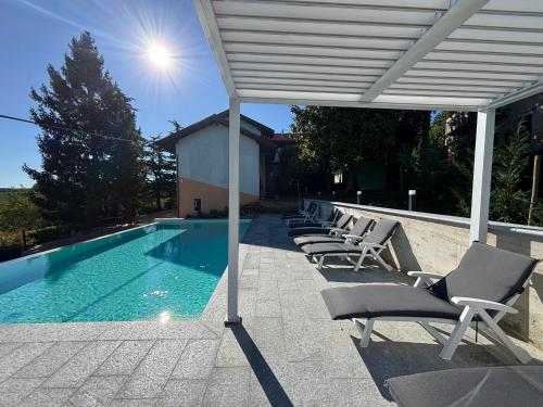 a row of chairs sitting next to a swimming pool at Relais Portaluna delle Langhe, Private Estate with Pool, 7 Bedrooms, Sleeps 18, Vineyard Views in Mango