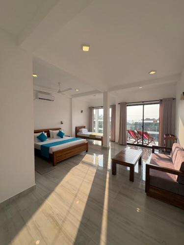a bedroom with two beds and a couch and a table at Crossing Royal in Mirissa